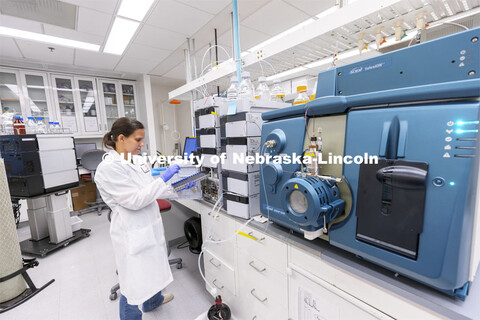 Lab Manager Anne Fischer works with a spectrometer in the background in the Proteomics and Metabolom