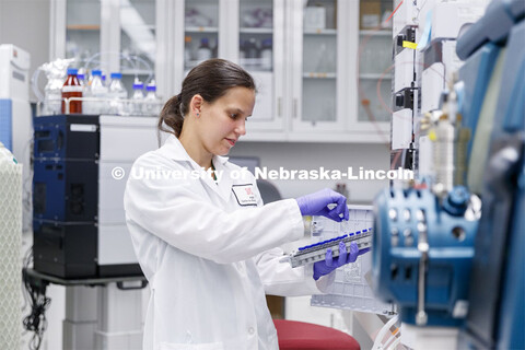 Lab Manager Anne Fischer works with a spectrometer in the background in the Proteomics and Metabolom