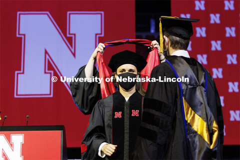 Mallory Van Haute receives her doctoral hood as advising Professor Devin Rose looks on. Graduate Com