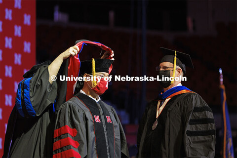 Qinnan Yang receives his doctoral hood as advising Professor Andy Benson looks on. Graduate Commence