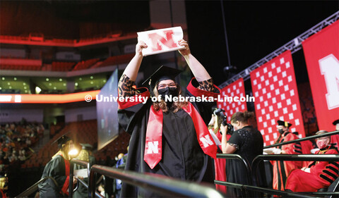 A new grad shows off her diploma to friends and family in the arena. Undergraduate Commencement at P