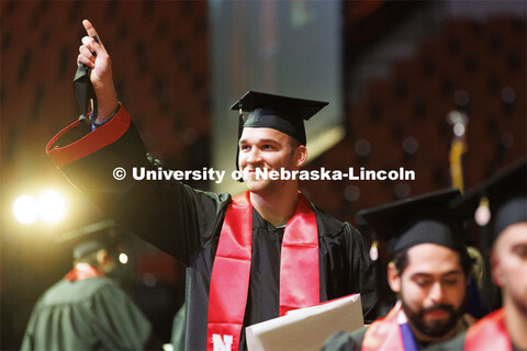 Joshua Wendland points to his friends and family after receiving his computer science diploma on sta