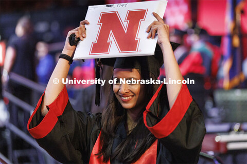 Tanima Shrivastava holds her computer science diploma over her head to celebrate as she is photograp