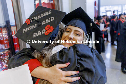 Katherine Lamb hugs Sarah Sloboth after graduating. Decorated mortarboard. Undergraduate Commencemen