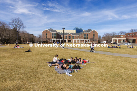 A group of young women take advantage of the nice weather and lay out and visit on the green space b