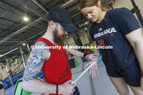 Nic Morre, Nebraska Ninja Warrior director, tapes over a torn blister on Leigh Jahnke’s hand so sh