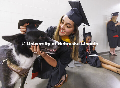 Vilma Maria Montenegro Castro adjusts the mortar board on her service dog, Matty, before the ceremon