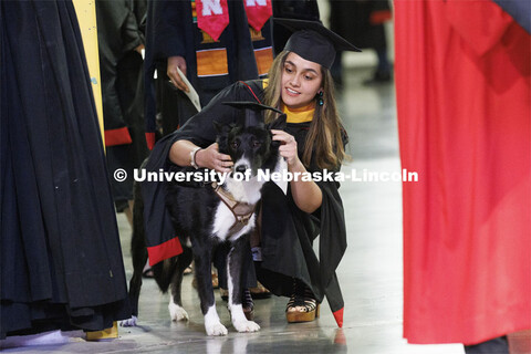 Vilma Maria Montenegro Castro adjusts the mortar board on her service dog, Matty, before the ceremon