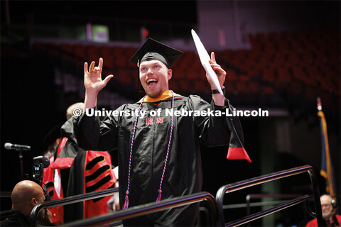 Sheldon Brummel gestures to family after receiving his masters degree. Graduate commencement in Pinn