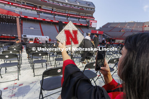 Grace Mann takes a photo of her mortar board before commencement. UNL undergraduate commencement in 