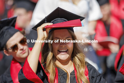 Hannah Ochsner uses the program to shade her eyes. UNL undergraduate commencement in Memorial Stadiu