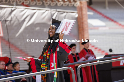 Chika Izuegbunam holds her diploma up as she walks off the stage so the cameras can show her on the 