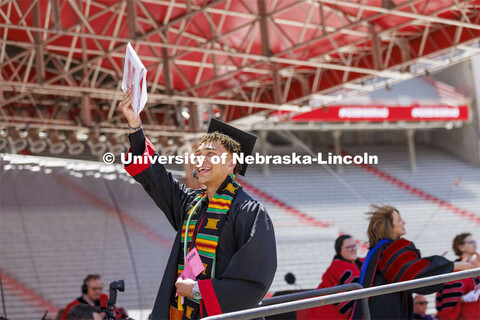 Hunter Johnson holds his diploma up as he walks off the stage so the cameras can show him on the vid