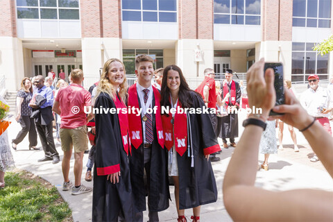 New grads pose for photos with their families. UNL undergraduate commencement in Memorial Stadium. M