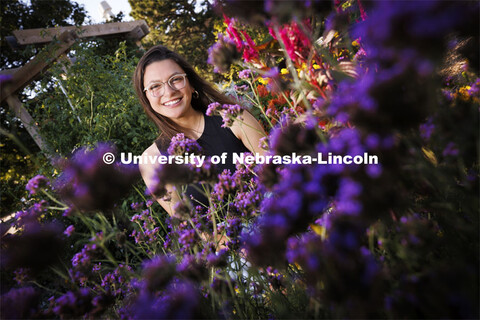 Isabella Villanueva smiles for a photo surrounded by flowers on East Campus. Villanueva is a sophomo