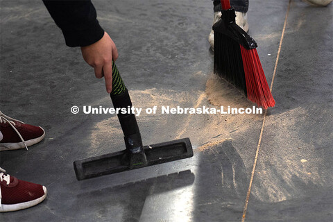 Students clean up the saw dust in the shop. Architecture design professor Aziza Cyamani is doing a w