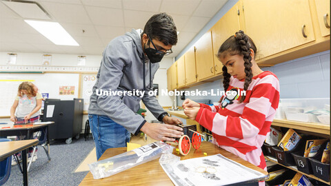 Rohan Tatineni helps a student assemble her rubber-band powered car. Nebraska honors students Spence