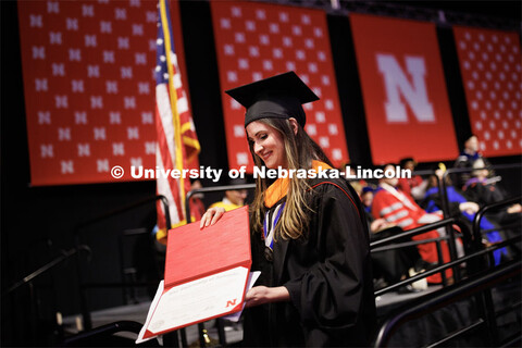 Tara Asgarpoor looks at her diploma as she walks off stage. Graduate Commencement in Pinnacle Bank A