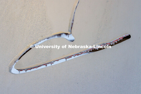 Icicles on the Torn Notebook glow red from the light of the Lied marquee. Ice and snow cover campus.