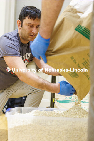 Andrew Brown helps pour the last of a large sack of oatmeal into a container for the volunteers to u