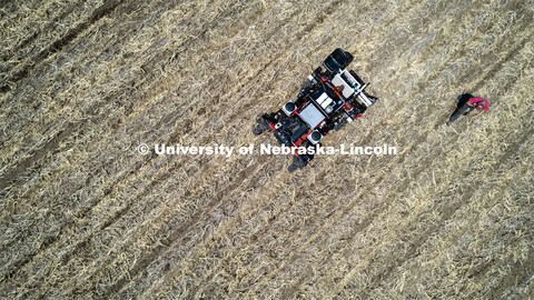 Graduate student Ian Tempelmeyer walks behind the robotic planter as it starts a row. The self drivi