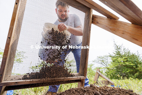 Dalton Carder, a senior in anthropology, pours a bucket of dirt through a sieve to see what history 