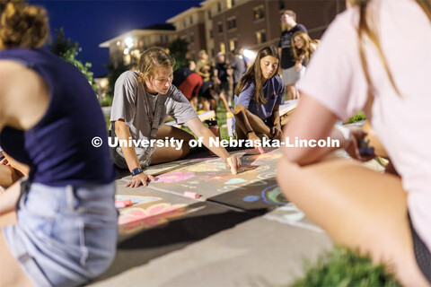 Brooke Poppert, a senior from St. Paul, Nebraska, center, chalks artwork on the sidewalk across from