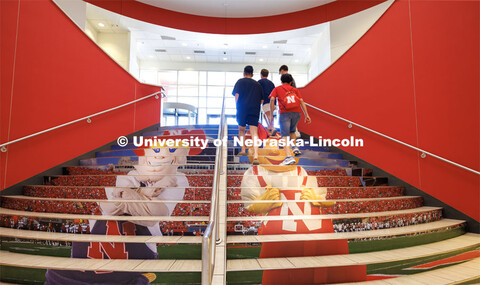 Students climb the stairs as Herbie Husker and Lil’ Red hang out on the steps leading up from the 