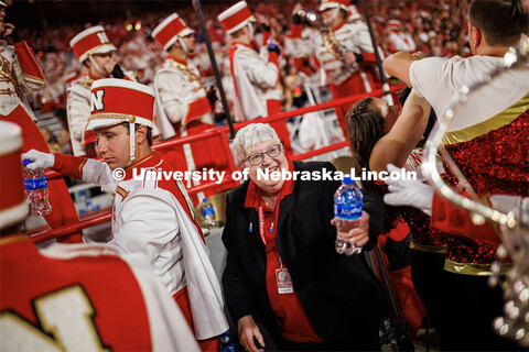 Rose Johnson with the Cornhusker Marching Band hands out water to the band members as they return to
