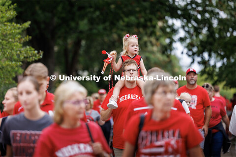 A young Husker fan brings her Barbie as she heads to the stadium on her dad’s shoulders. Nebraska 