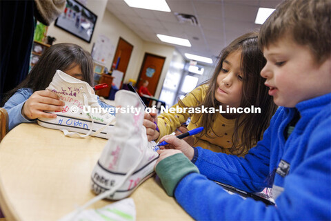 Lillian, center, along with Bella, left, and Holden decorate Crandall Blake’s high tops. Crandall 