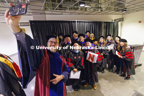 Doctor of Educations graduates and their advising professors pose for a selfie following the ceremon