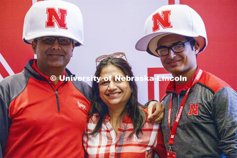 Shrey Agarwal poses with his family wearing oversized Nebraska baseball caps. Admitted Student Day i