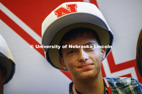 Caleb Kelly poses wearing oversized Nebraska baseball caps. Admitted Student Day is UNL’s in-perso