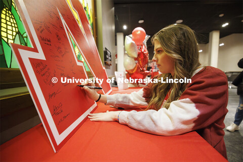 Bailey Ridder of Broken Bow, Nebraska, signs a large “N” poster inside the Nebraska Union. Admit