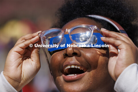 Samya Lee, a freshman from Omaha, smiles as she can see the eclipse by holding her eyeglasses over t