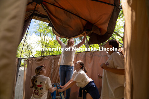 Members of Tri Delta hold a ladder steady while Rachel Nelson pulls the roof of a pergola over the t