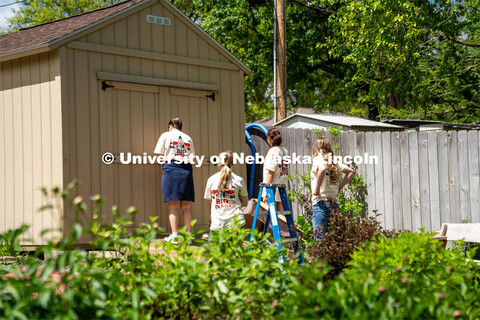 Members of Tri Delta, Sophie Helm, Alyssa Dunlap, Rachel Nelson, and Kate Freeman, go to a homeowner