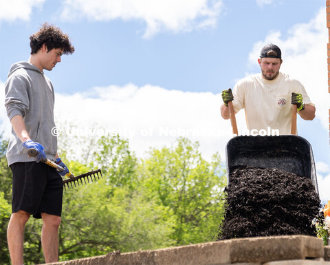 Pi Kappa Alpha’s Grant Breidenbach waits for Ethan Heinemann to supply more mulch for him to sprea