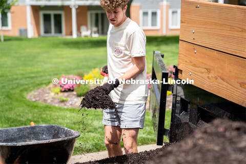 Daniel Koland of Pi Kappa Alpha fills a wheelbarrow with mulch at the Van Dorn Villa Retirement Livi