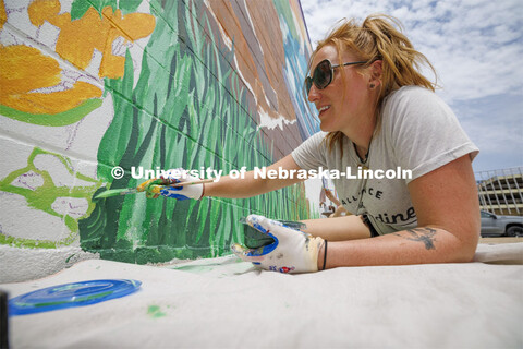 Kyren Gibson with the Carnegie Art Center in Alliance paint at the bottom of the mural. Gibson came 