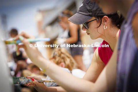 Taryn Hamill, a senior in art, paints on the mural as the group works on the grasses and flowers acr