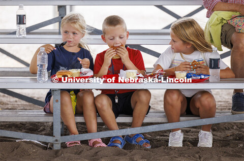 Three young kids eat their lunch on the bleachers at the fair. 4-H Polk County Fair in Osceola, Nebr