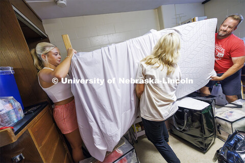 Addison Hasenpflug with her parents Amy and Rick wrestle a mattress cover onto her bed in Schramm Ha