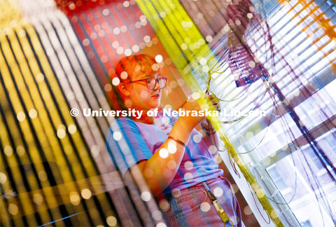 Eden Wilder works to untangle lights from a multi-colored screen in her Eastside Suites Residence Ha