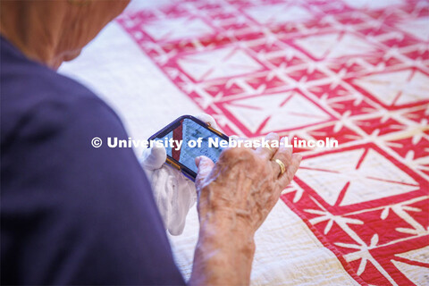 Volunteer Susan Macy looks at a photo of the quilt on Carolyn’s phone to read the name easier. Int