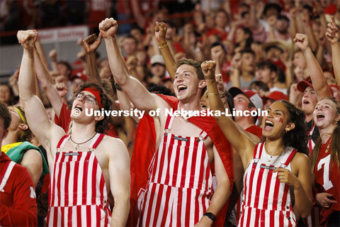 Cheering fans in the student section wear red and white striped overalls. Nebraska vs. Illinois foot