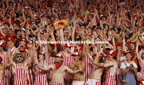 Cheering fans in the student section wear red and white striped overalls. Nebraska vs. Illinois foot