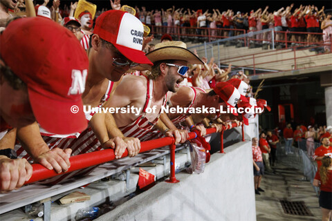 Cheering fans in the student section wear red and white striped overalls. Nebraska vs. Illinois foot