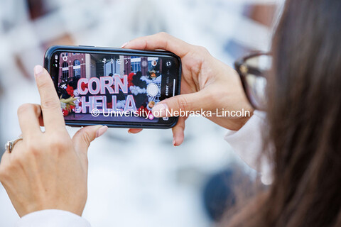 A student uses their phone to take a photo of the Cornchella sign. 2024 Homecoming celebration. Octo
